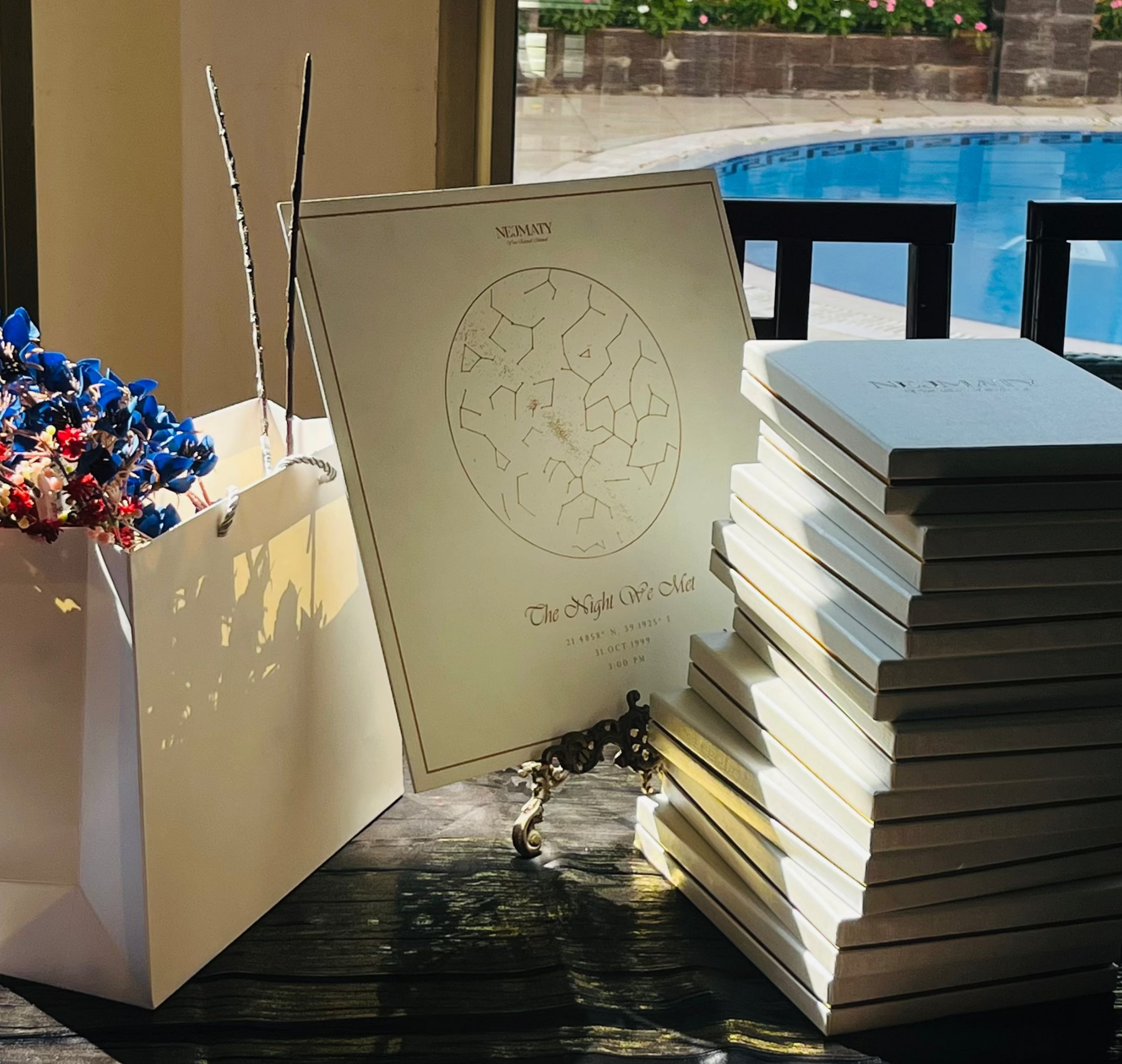 Stack of starmap boxes on a table with decorative items and a view of a pool and garden.